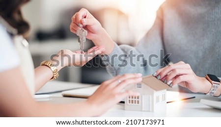Buying real estate and agreement concept. Real estate agents agree to buy a home and give keys to clients at their agency's offices.  Royalty-Free Stock Photo #2107173971