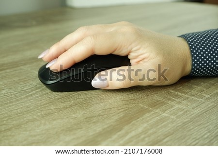 A woman's hand holds a computer mouse. Working with the mouse. Close-up photo on a white background.