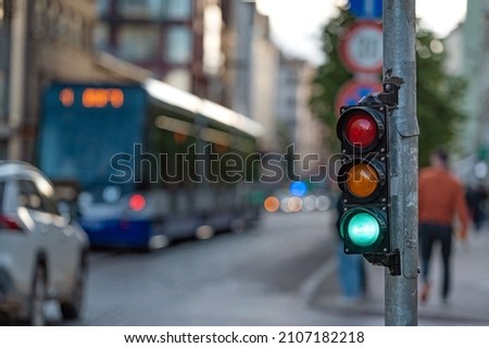 blurred view of city traffic with traffic lights, in the foreground a semaphore with a green light Royalty-Free Stock Photo #2107182218