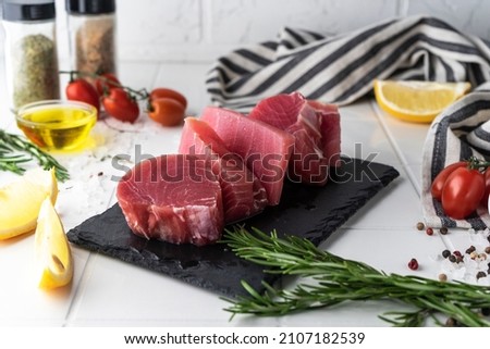 Fresh tuna fillet steaks with spices, vegetables and herbs on a plate. Preparing tuna for baking. High quality photo