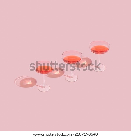 Three elegant wine glasses on pastel pink background. Trendy and minimal romantic Valentine's day aesthetic.