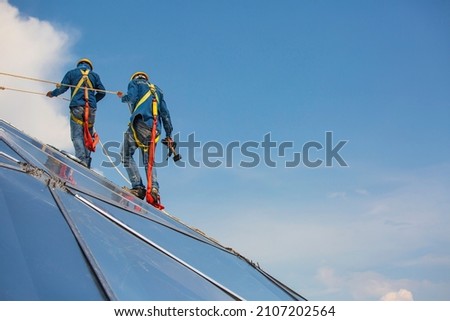 Male two workers rope access height safety connecting with a knot safety harness, roof fall arrest and fall restraint anchor point systems ready to ascending, construction site oil tank dome Royalty-Free Stock Photo #2107202564
