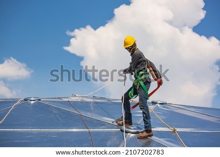 Male workers rope access height safety connecting with a knot safety harness, roof fall arrest and fall restraint anchor point systems ready to ascending, construction site oil tank dome Royalty-Free Stock Photo #2107202783
