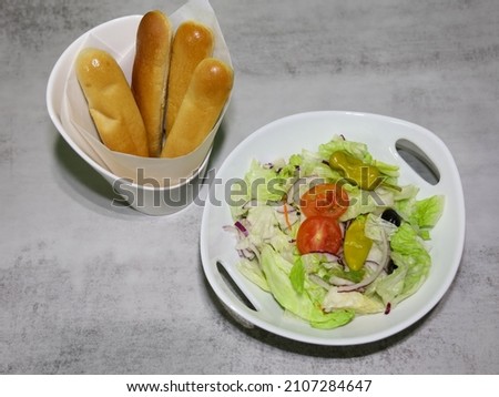 Breadsticks and salad with tomato, black olives, red onion and pepperoncini peppers.