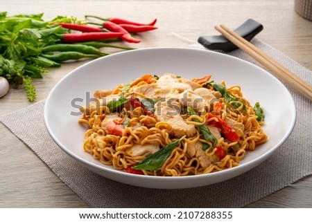 Spicy stir fried instant noodle with sliced chicken breast and thai basil leaves in white plate Royalty-Free Stock Photo #2107288355