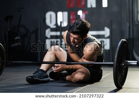 Young Caucasian men grab his arm and shoulder and feeling painful while weight lifting exercise inside of sport gym. Sport accident, overtrain. Royalty-Free Stock Photo #2107297322