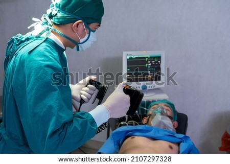 Selective focus at defibrillator while doctor use it to pump at chest of unconscious with low heart rate patient to save life while doing medical surgery inside of operating room. Emergency aid, CPR.