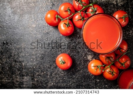 Juice from ripe tomatoes in a glass. On a rustic dark background. High quality photo