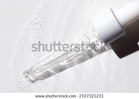 Liquid oil serum drop in pipette isolated on white background. Retinol, aha, bha acid, collagen skincare fluid, photo with shallow depth of field. Gold essence in dropper for beauty treatment. Royalty-Free Stock Photo #2107325231