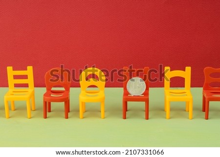 a row of chairs, one of which has a metal coin of one Russian ruble. pending ruble