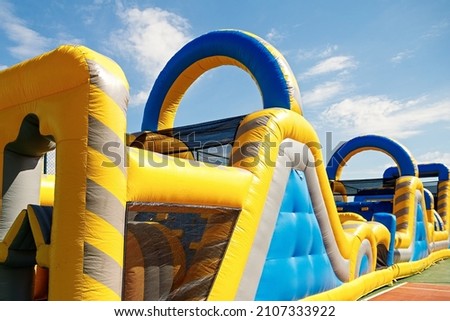 Inflatable obstacle course slide for kid games or team building outdoor activities. Royalty-Free Stock Photo #2107333922