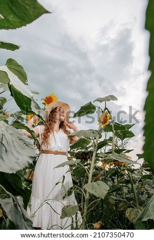 Beautiful joyful woman in blooming sunflower field. Smiling girl with sunflower on field, outdoors. Beautiful silhouette mysterious enjoy nature woman bright photo.