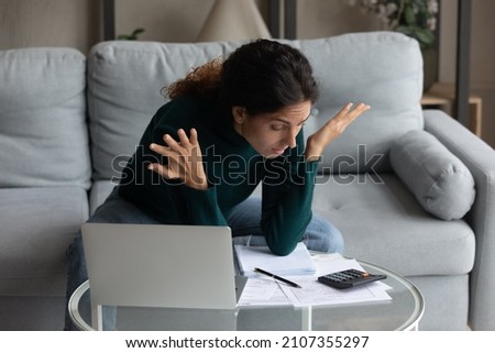 Unhappy anxious millennial gen latin woman feeling stressed calculating domestic expenses or managing monthly budget using computer at home, suffering from lack of money or having financial problems. Royalty-Free Stock Photo #2107355297