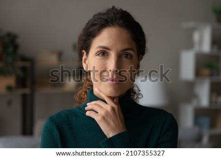 Head shot portrait beautiful calm woman touching chin, feeling self confident at home, rental tenancy concept. Happy attractive positive lady with perfect teeth and tidy hairstyle looking at camera. Royalty-Free Stock Photo #2107355327