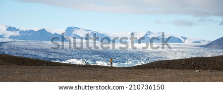 Panorama picture of a man standing at the icelake Jokulsarlon