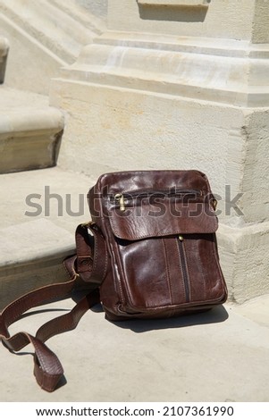 Outdoor photo of a brown leather Messenger bag.