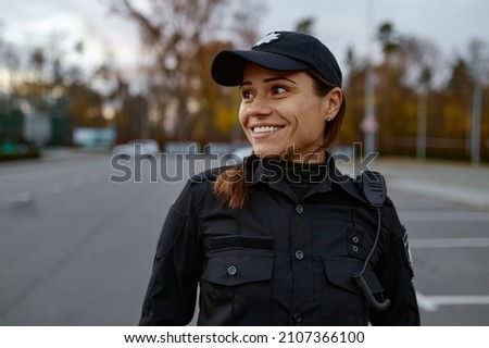 Portrait of smiling police woman on street Royalty-Free Stock Photo #2107366100