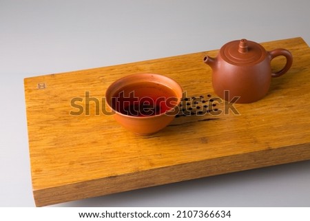 Teapot and cup with freshly brewed pu-erh tea. A set on a wooden table for tea ceremonies.
