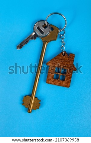 Keys with a keychain in the form of a house.  Rent apartments, Real Estate and buying a house idea. Blue background