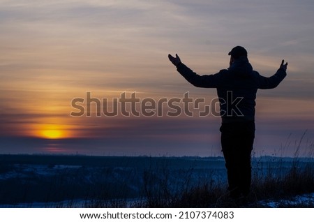 Prayer. Repentance. A man with his hands raised against the sky. Pray to God. Worship, against the backdrop of sunset