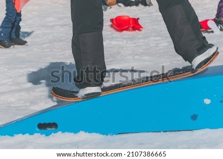 A close-up shot of a Caucasian man sliding down a slope on a snow skate at a ski resort in France