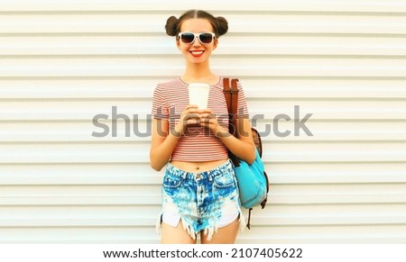 Portrait of happy smiling young woman drinking a coffee wearing a striped t-shirt with cool hairstyle on white background