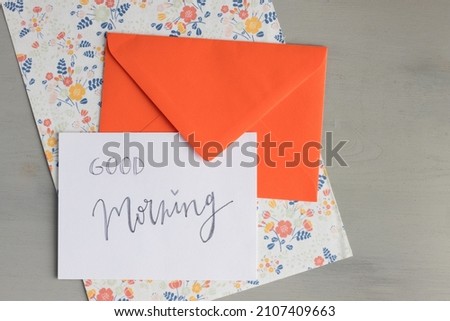 Happy message written with lettering over an opened intense red envelope on a fun floral sheet. Horizontal photo.