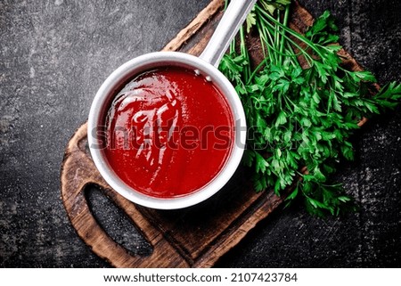 Tomato sauce on a wooden cutting board. On a black background. High quality photo