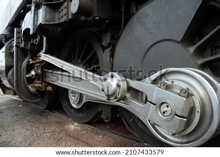 Foreshortened view of a silve metal valve gear assembly main drive rod linkage and drive wheels with on a black steam locomotive Royalty-Free Stock Photo #2107433579