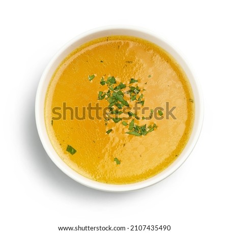 bowl of fresh chicken broth with chopped parsley isolated on white background, top view