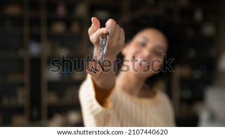 Close up focus on keys in hands of smiling young African American woman, celebrating moving into rental apartment. Sincere happy female homeowner purchasing first dwelling, real estate, tenancy. Royalty-Free Stock Photo #2107440620