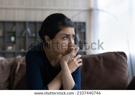 Thoughtful stressed young Indian ethnic woman looking in distance, considering psychological problem solution, suffering from depression or feeling doubtful making difficult decision at home. Royalty-Free Stock Photo #2107440746