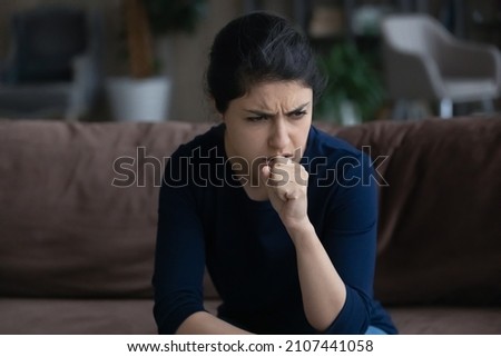 Unhealthy young Indian woman coughing, suffering from bronchitis disease or painful uncomfortable feelings in throat, caught cold, first flu grippe covid19 symptoms, immunity concept. Royalty-Free Stock Photo #2107441058