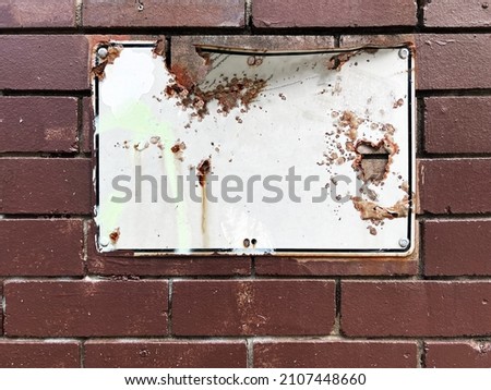 Old rusty aged weathered street wall sign on brown painted brick background