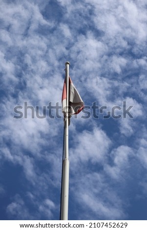 Indonesia flag with white and red against cloudy sky 