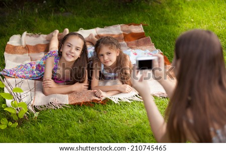 Two little sisters smiling for photo while having fun on grass at park