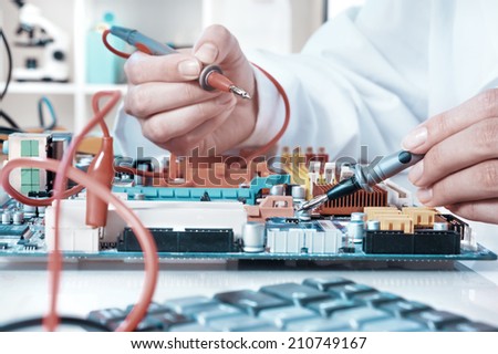Electronics repair service, hands of female tech fixes an electronic circuit Royalty-Free Stock Photo #210749167