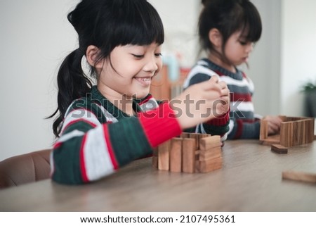Cheerful Asian girl playing with wooden building blocks. Having fun and learning creativity. smart kid concept.