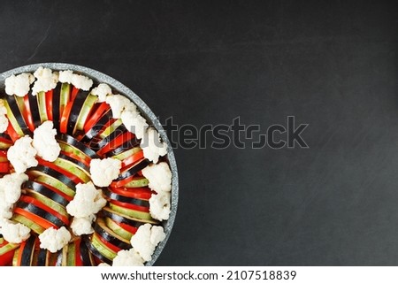 Ratatouille dish of fresh vegetables in a frying pan on a dark background. Traditional French vegetarian dish