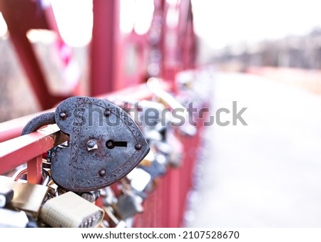 Closeup heart shape of vintage rusty steel padlock hold at the red bridge, depth of field. Traditional symbol for strengthen, loyalty, forever mutuality and eternity love of couple. Valentine concept.
