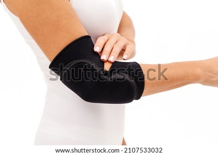 A Woman Wearing Elbow Brace Over White Background. Horizontal photo Royalty-Free Stock Photo #2107533032
