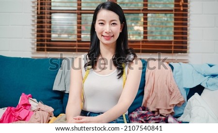Portrait of Asian stylist fashion influencer designer women owner of online business, e-commerce feeling happy and confident smiling to camera on sofa in living room at home.