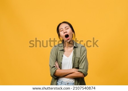 Portrait of Young Asia lady with negative expression, bored yawning tired covering mouth with hand in casual clothing isolated on yellow background with blank copy space. Facial expression concept Royalty-Free Stock Photo #2107540874