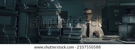 Smiling office worker sitting at desk and doing a repetitive job, he is stamping files