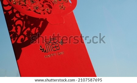 Chinese Lunar New Year celebrations theme red envelopes with blessing words contained money as a gift on blue sky background with light and shadow. The Chinese word means happiness and good fortune.