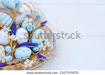 Banner. Easter card of 2022. Festive white and blue cherry blossoms on an iron tray on a white wooden background. Minimal concept.