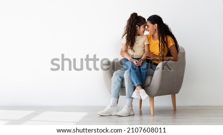 Mother And Child Bonding. Loving Young Mom And Little Daughter Embracing While Relaxing In Armchair At Home, Happy Middle Eastern Family Enjoying Spending Time Together, Panorama With Copy Space Royalty-Free Stock Photo #2107608011