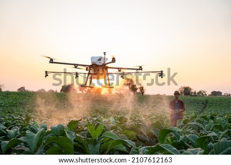 Asian farmers fly drones to spray hormonal fertilizers in tobacco fields, Drone of agricultural technology concept Royalty-Free Stock Photo #2107612163