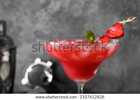 Glass of tasty strawberry margarita on grunge background, closeup
