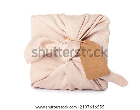 Gift wrapped in fabric with tag on white background